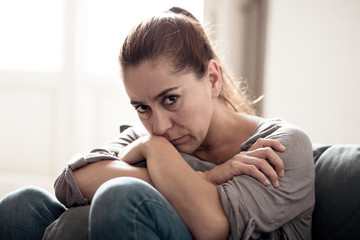 Young woman suffering from depression feeling sad and lonely on sofa at home