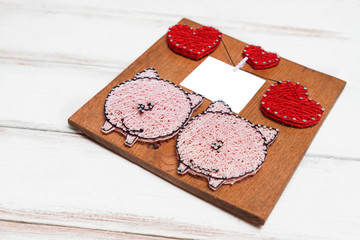 on a wooden white background-handmade wooden panel with images of hearts and pigs .In the center of a sheet of insulated paper
