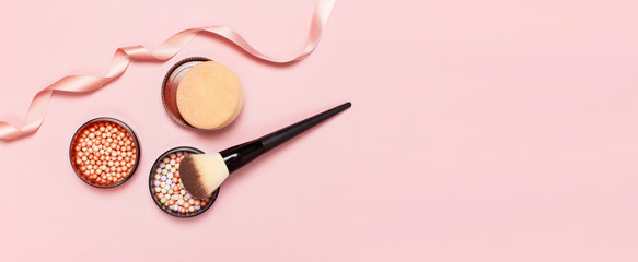 Ball pearl blush, face powder, makeup brush and pink ribbon on a pastel pink background top view Flat Lay with copy space. Various cosmetic products, Makeup Accessories.