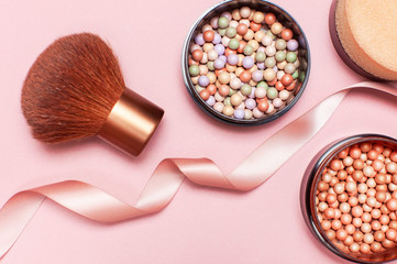 Ball pearl blush, face powder, makeup brush and pink ribbon on a pastel pink background top view Flat Lay with copy space. Various cosmetic products, Makeup Accessories.