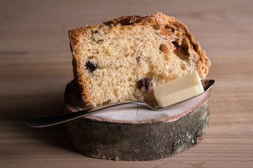 A piece of homemade cake with a piece of  butter on a spoon on a wooden substrate