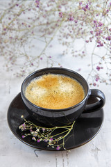 Black coffee on a light background decorated with flowers