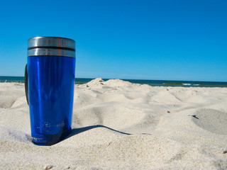 Cup of coffee on white sand on the beach by the sea. Concept: holidays,  relaxing on the beach on the sea side