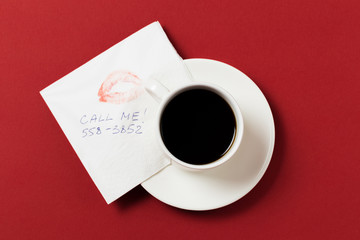 Obraz na płótnie Canvas paper napkin with a kiss and coffee cup on red background.