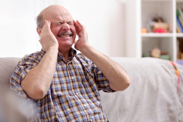 Obraz premium Senior man with mustache having a headache at home