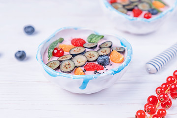 Whipped quark mousse with raspberries, blueberries, red currant and winter cherry on a white background