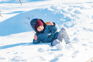 Fototapeta na wymiar The boy walks in the winter outside and wallows in the snow.