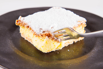 Napoleonka cake - a Polish type of cream pie - sprinkled with powdered sugar, eaten with a fork