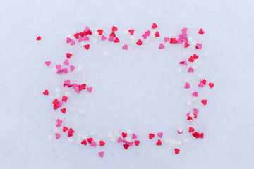 frame of scattered red hearts in the snow. concept valentine's day. space for text