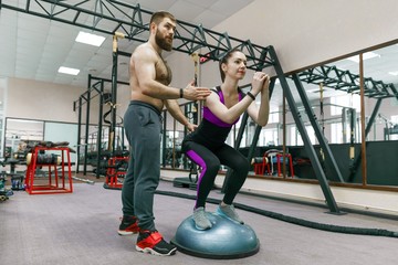 Personal fitness trainer coaching and helping client woman making exercise in gym. Sport, teamwork, training, people concept.