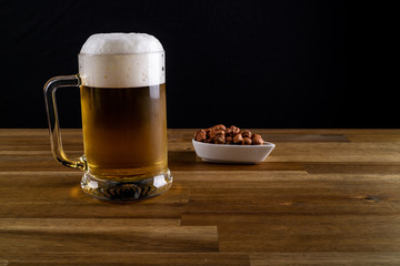 Cold beer with nuts on black background
