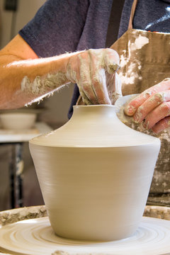 Detail of artist potter in the workshop sculpting ceramic vase