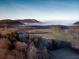 Aerial of a fog-covered rock on a sunny winter day