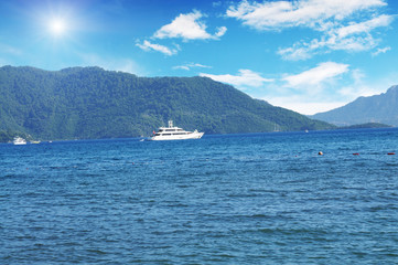 Fototapeta na wymiar Boats and yachts in the sea with mountains and sky with sun
