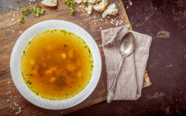 Beef soup with carrots and herbs on a dark background