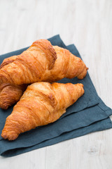 Tasty buttery croissants on old wooden table.