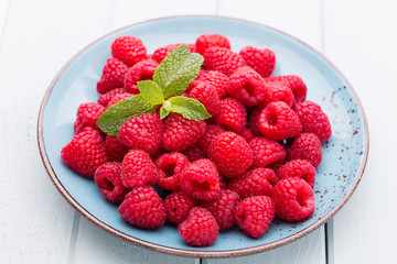 Fresh raspberries in a plate on a  vintage background.