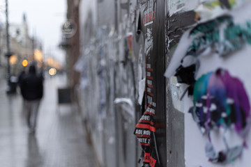 Ulica w zimowe popołudnie z obdrapanym murem pełnym plakatów - obrazy, fototapety, plakaty