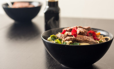 A bowl of homemade ramen topped with slices of steak and fresh red chilli