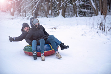 Fototapeta na wymiar young guy and a girl ski tubing in the winter ride down a hill