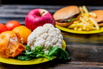 junk food or healthy vegetables and fruits on dark wooden table isolated b