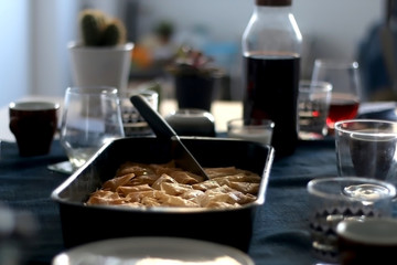 Pan of baklava on a table with coffee and wine. Baklava is traditonal Turkish pastry desset. Selective focus, moody lighting.
