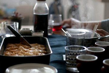 Pan of baklava on a table with coffee and wine. Baklava is traditonal Turkish pastry desset. Selective focus, moody lighting.