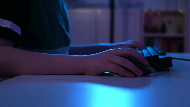 Close up of boy using a computer mouse at night while playing video games