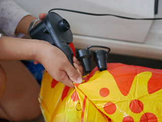 A woman's hands holding and using mini air pump, connected to the car plug, to inflate a rocking...