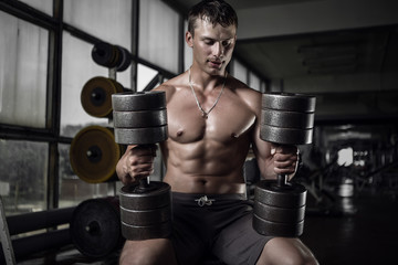 Fitness guy holding huge dumbbells