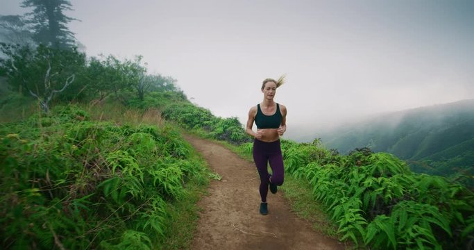 Gorgeous fitness woman runs along beautiful mountain trail