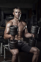 Fitness guy holding huge dumbbells