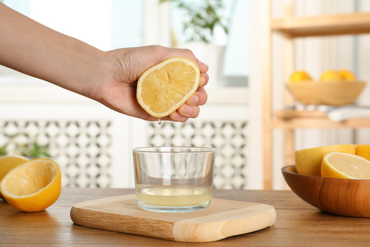 Woman squeezing lemon juice into glass bowl at table