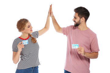 Happy young people with driving licenses on white background