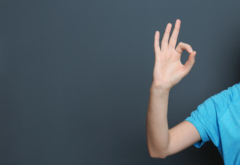 Young woman showing OK gesture on color background. Space for text