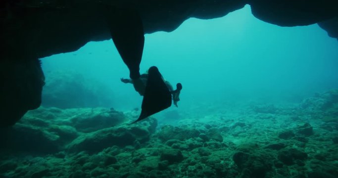 Adventurous freediver woman exits epic underwater cave and surfaces