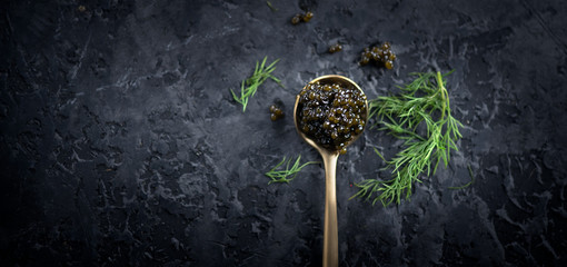Black caviar in a spoon on dark background. Natural sturgeon black caviar closeup. Delicatessen....