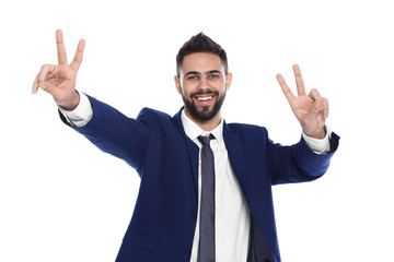 Happy young businessman showing victory gesture on white background