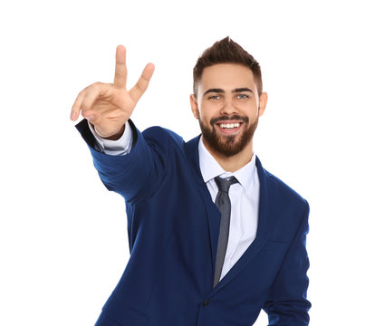 Happy young businessman showing victory gesture on white background
