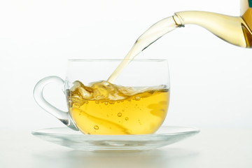 Tea pouring into tea cup on white background