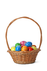 Decorated Easter eggs in wicker basket on white background