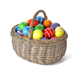 Decorated Easter eggs in wicker basket on white background