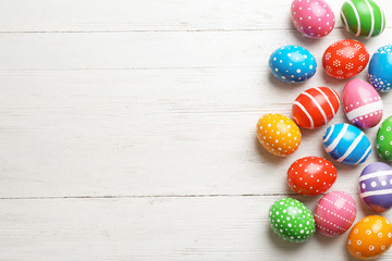 Decorated Easter eggs and space for text on wooden background, top view