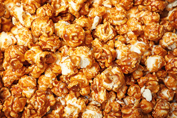 Sweet tasty caramel popcorn as background, top view