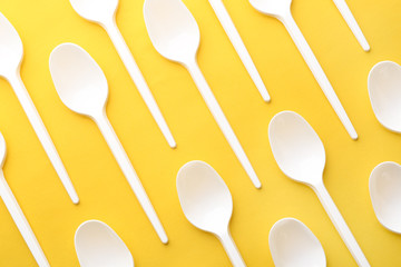 Plastic spoons on color background, top view. Picnic table setting