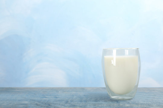 Glass with fresh milk on table against color background. Space for text