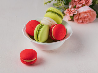 Macaron or macaroon french coockie on light background with spring flowers, pastel colors.