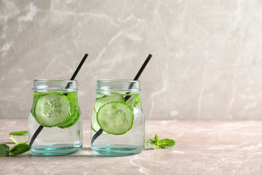 Jars with fresh cucumber water on table. Space for text