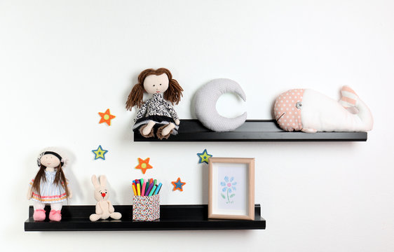 Cute toys and picture on shelves in child room