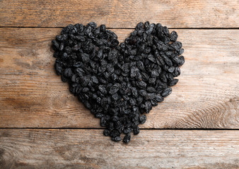Heart shape of raisins on wooden background. Dried fruit as healthy snack